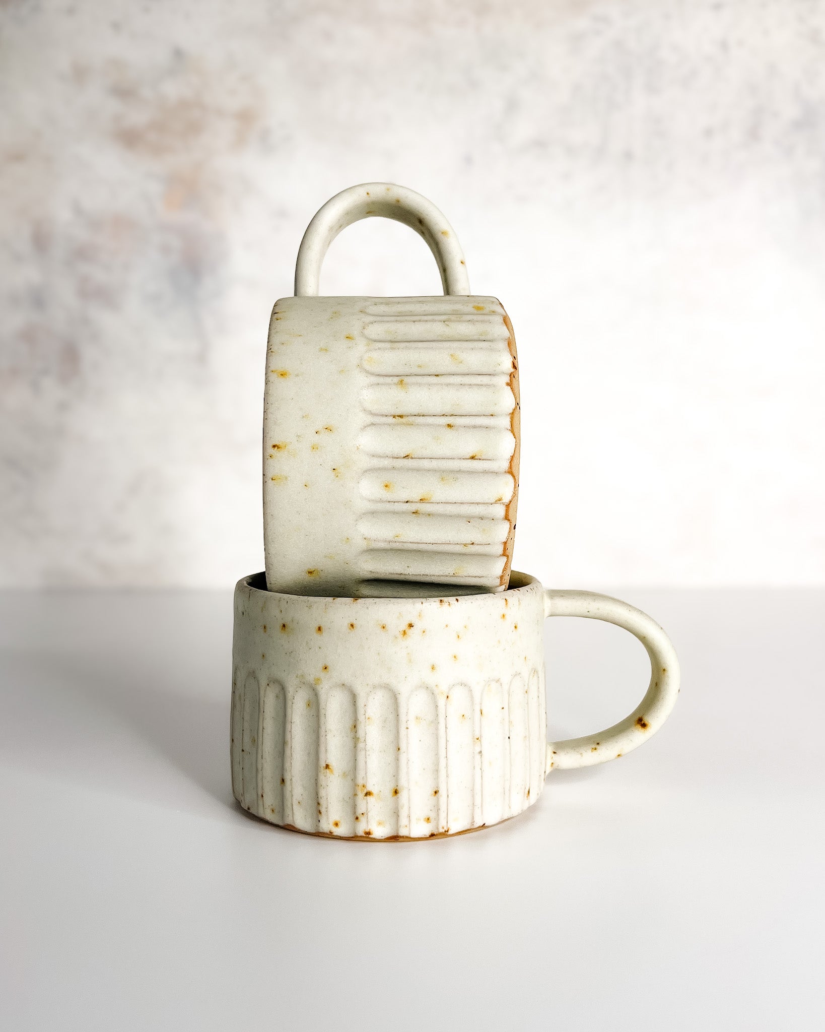 Hand-thrown carved and speckled stoneware cup with speckle glaze, ideal for coffee or tea.
