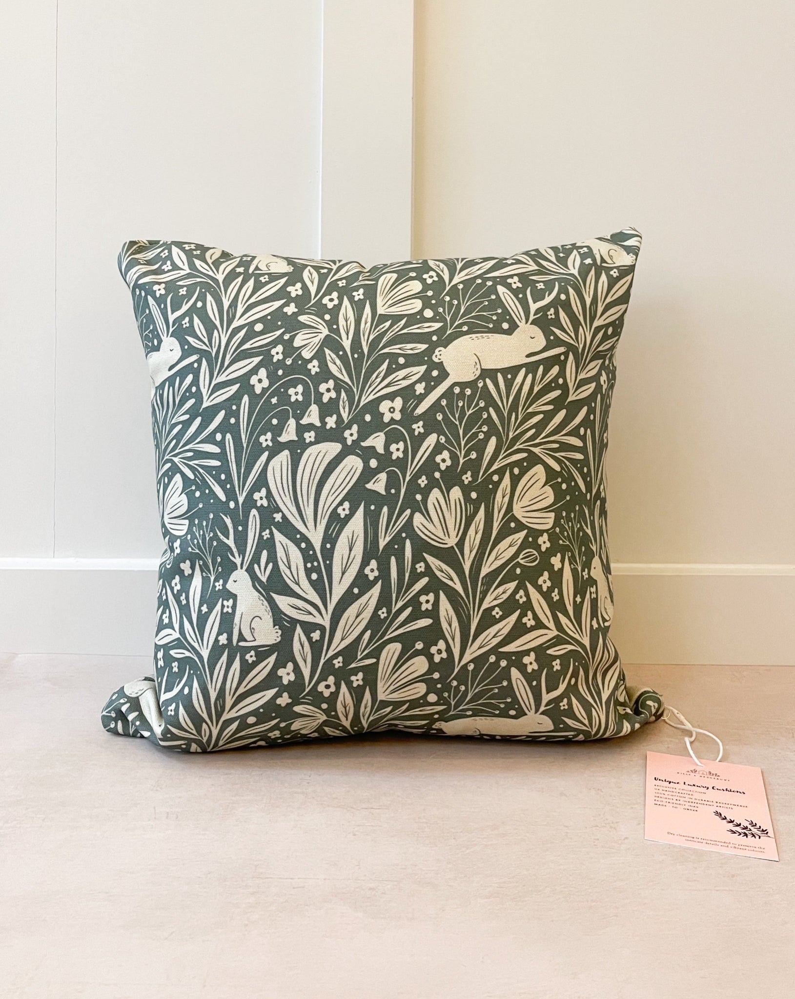 Botanical-inspired decorative cushion with lush green and floral patterns, handmade in the UK from sustainable basketweave cotton.