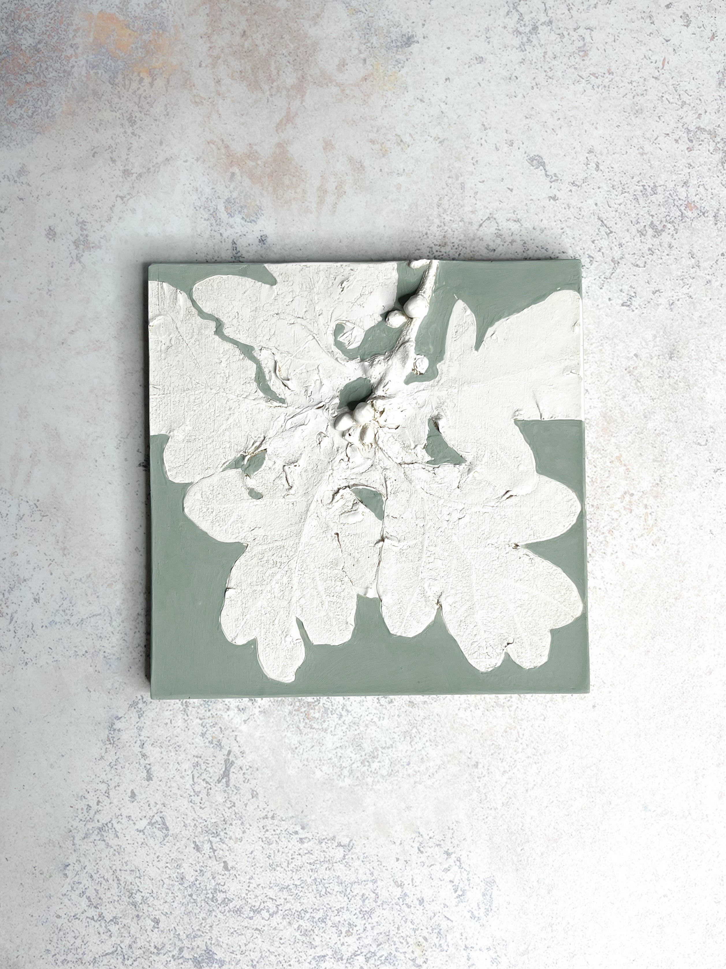 Handcrafted botanical relief tile featuring oak leaves, hand-painted in sage green, symbolising strength and resilience.