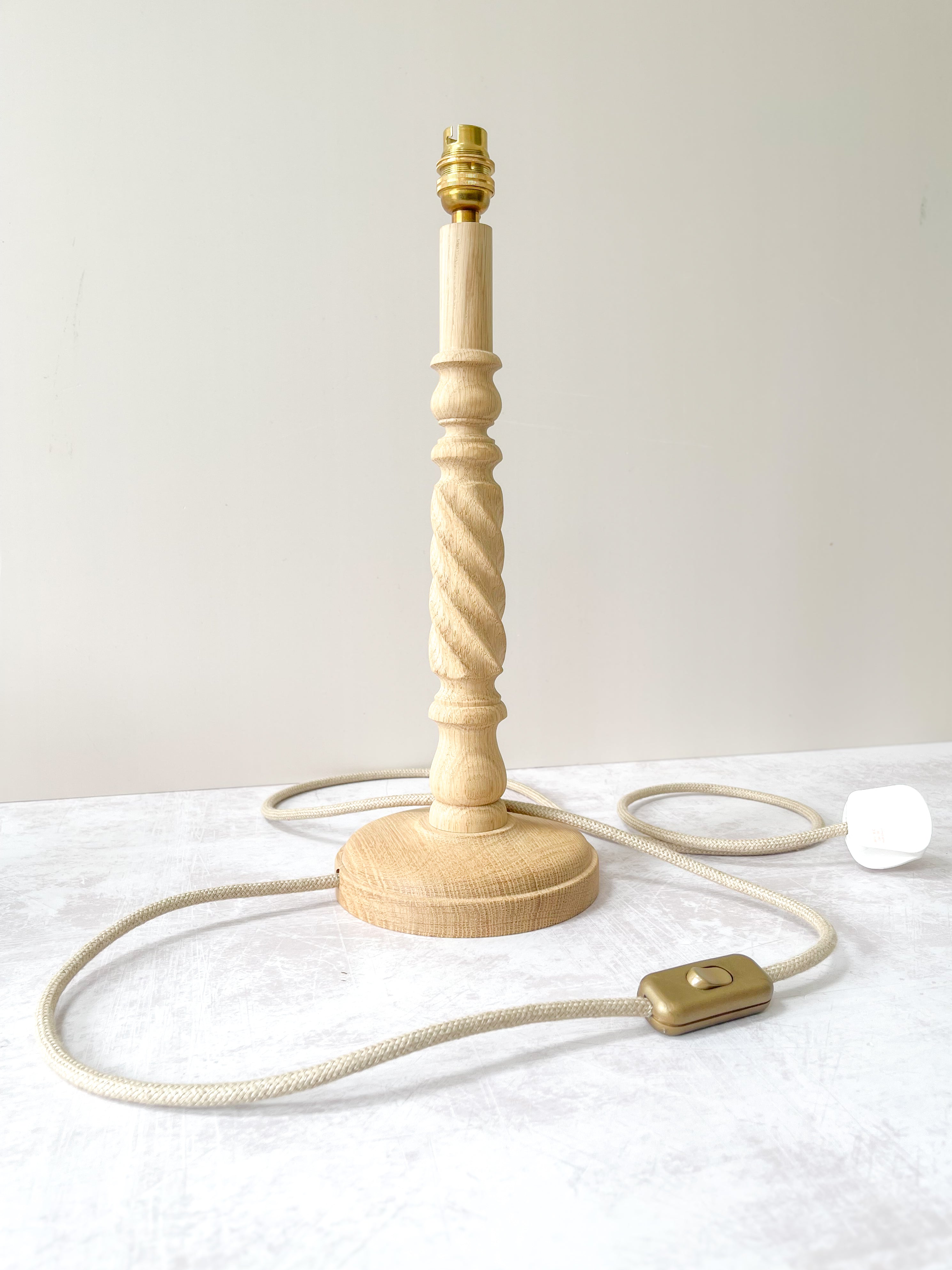 Handmade oak lamp base with twist detail, brass fittings, and neutral jute cable – crafted in Britain by Hills & Hedgerows.