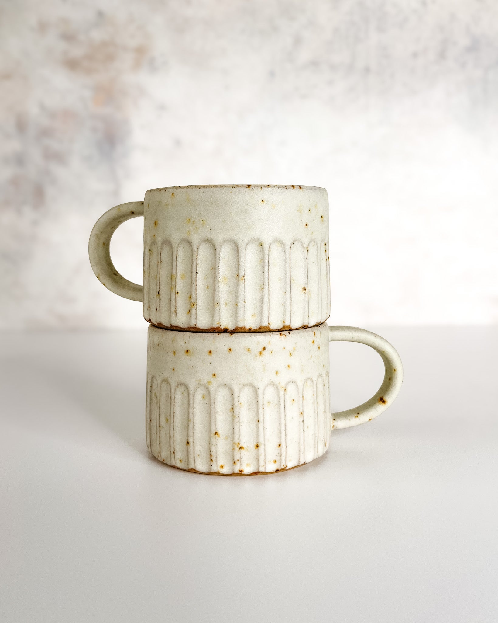 Hand-thrown carved and speckled stoneware cup with speckle glaze, ideal for coffee or tea.