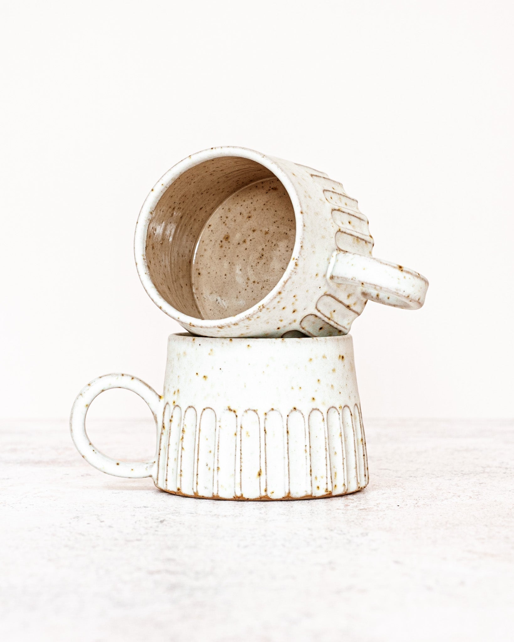 Handthrown pottery, featuring large stoneware mugs, stylish ceramic travel cups with silicone lids and speckled clay candle holders.