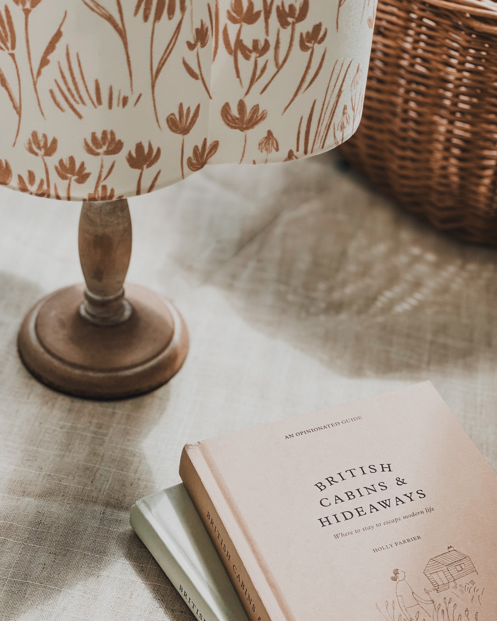 Botanical scalloped handmade lampshade with travel books on unique cabins and hideaways
