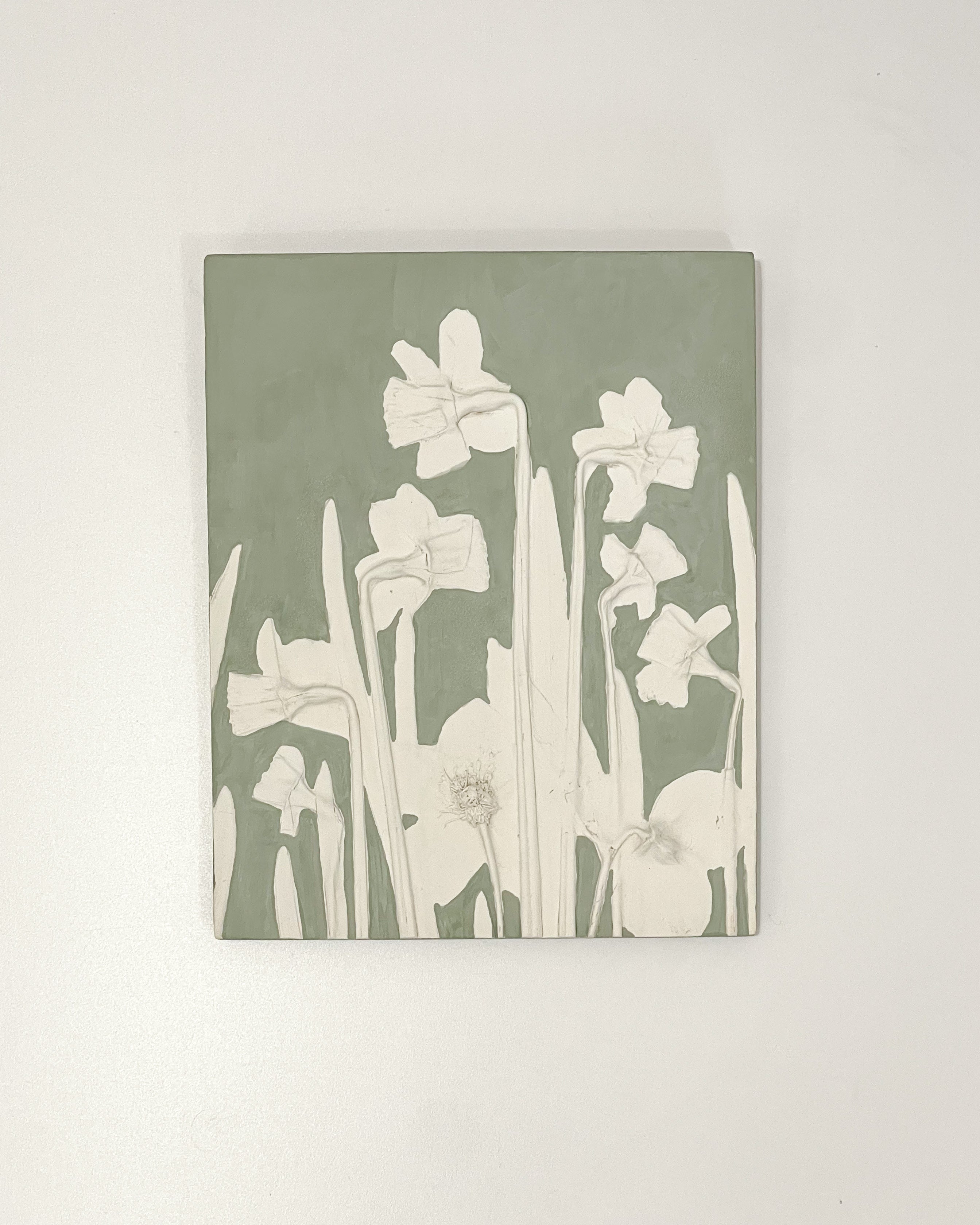 Handmade daffodil botanical relief in sage green, crafted from a single-use clay mold with a metal D-ring hanger, perfect for rustic and spring-inspired home decor.