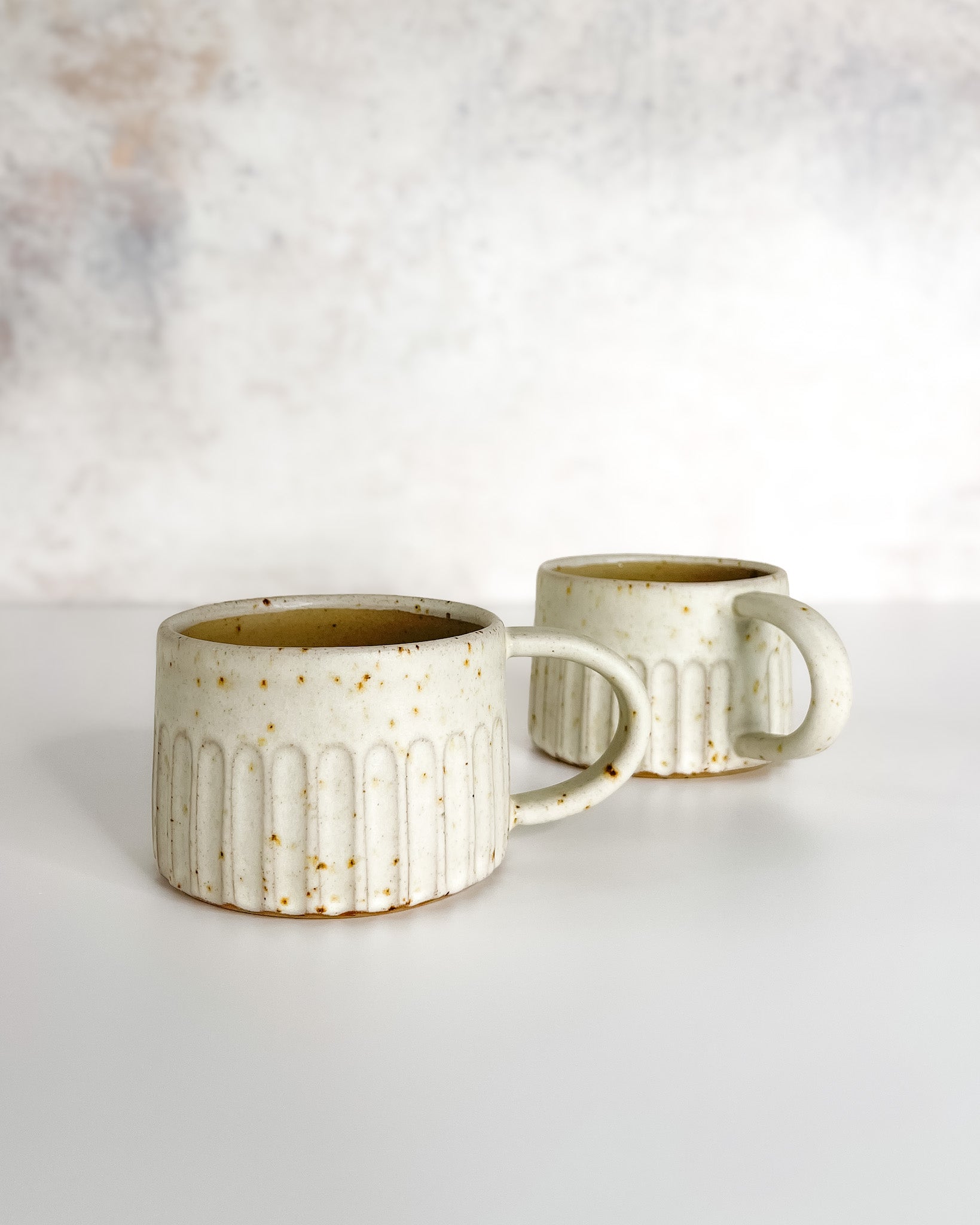 Hand-thrown carved and speckled stoneware cup with speckle glaze, ideal for coffee or tea.
