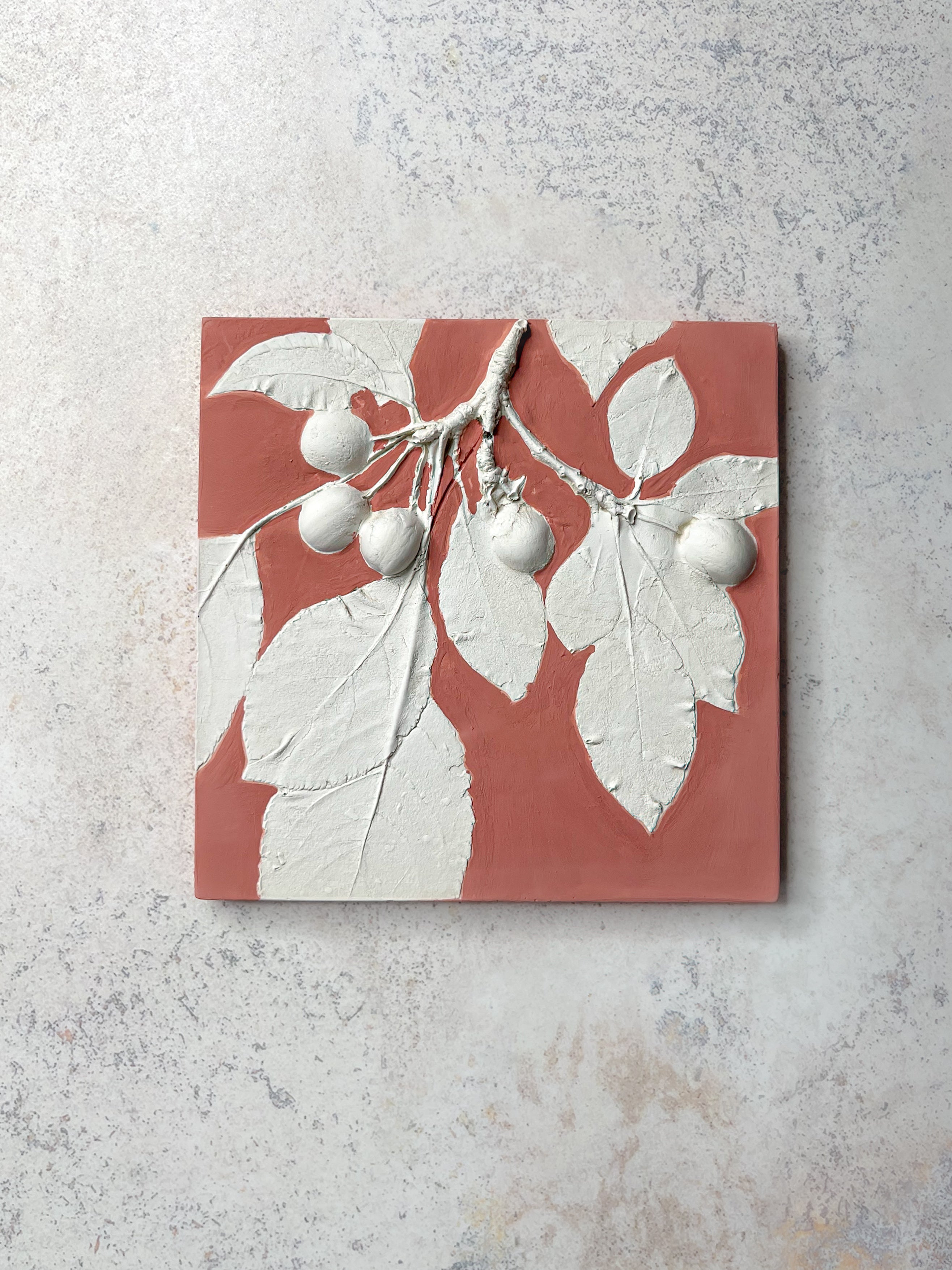 Handcrafted botanical relief tile featuring crab apple branch, hand-painted in muted coral, symbolising renewal and growth.