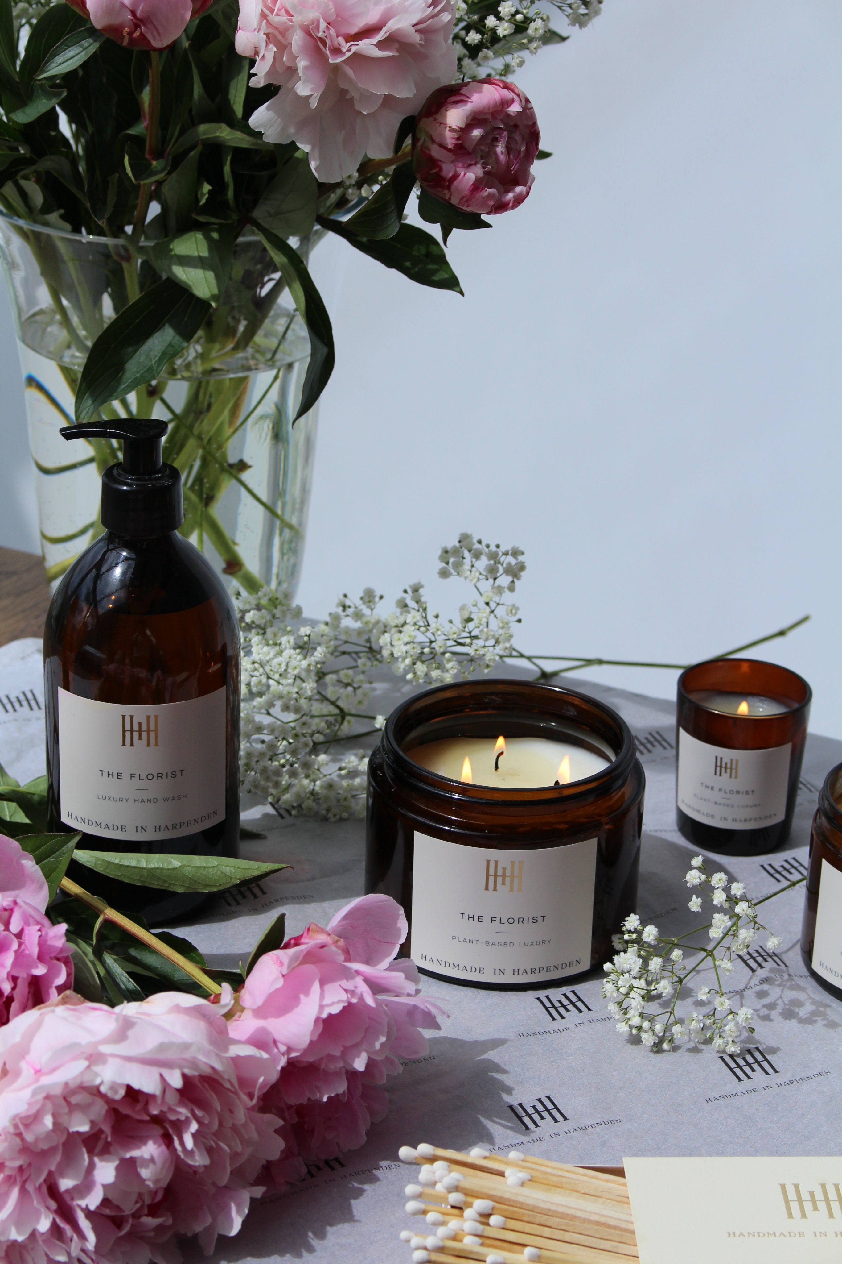 Candle and bottles on a table with flowers and matches