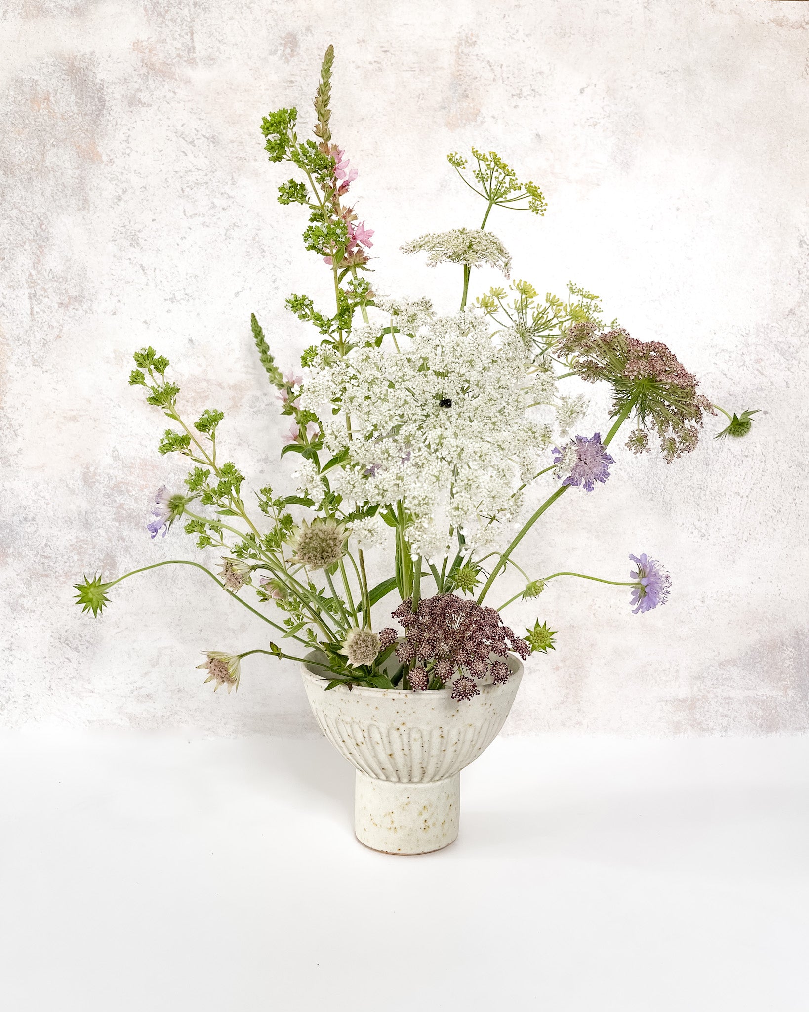 Hand-thrown ceramic Ikebana vase set with speckled clay, carved texture, and an elevated base, featuring a stem holder for floral displays.