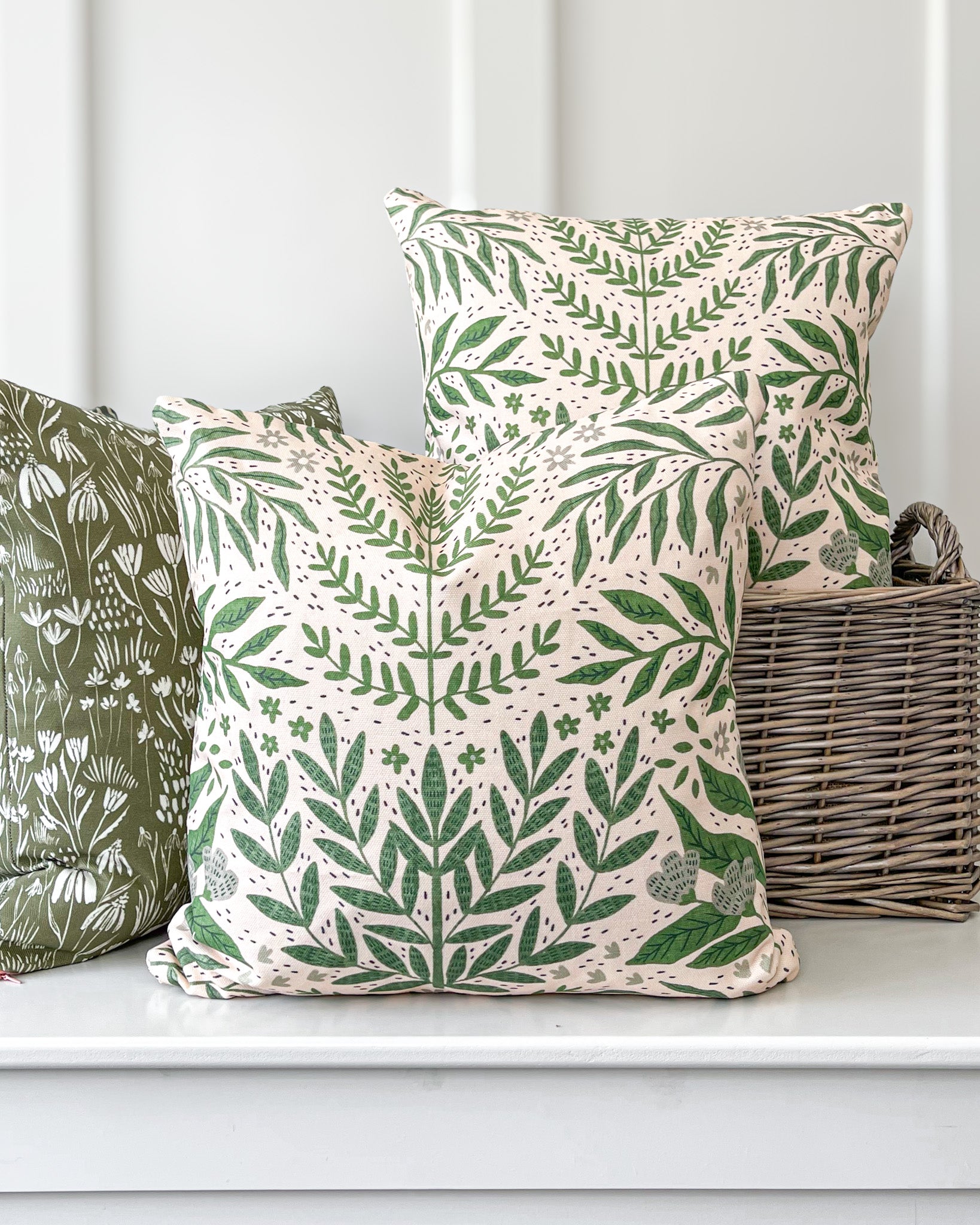 Tickling Greens Cushion featuring a green leafy pattern over a blush cream background, made of basketweave cotton with a duck feather insert, designed by independent artists.