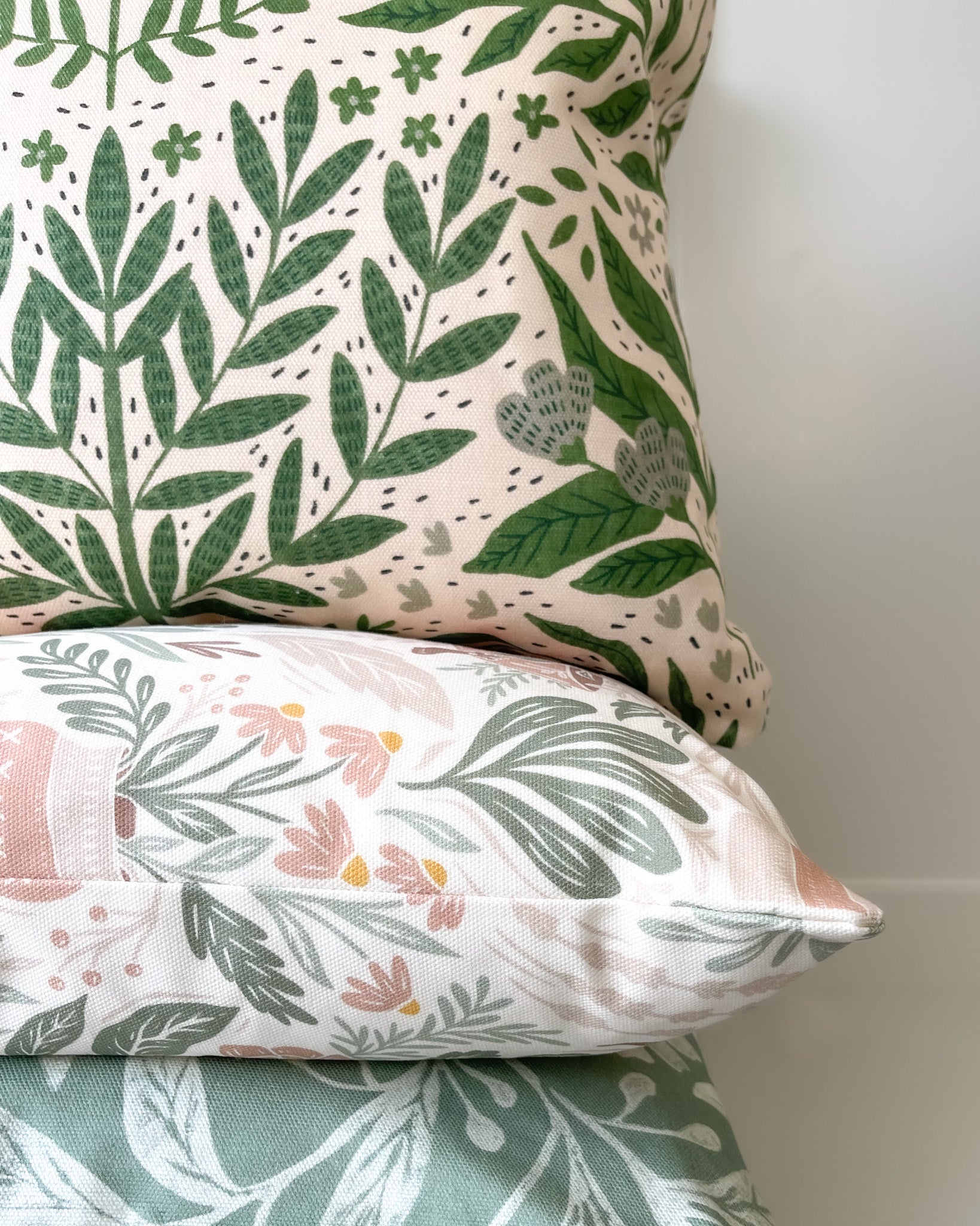 Tickling Greens Cushion featuring a green leafy pattern over a blush cream background, made of basketweave cotton with a duck feather insert, designed by independent artists.